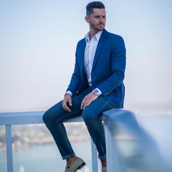 A man sitting on a balcony wearing a blue suit.