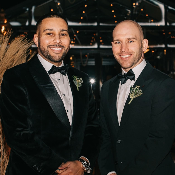 Two men wearing tuxedos, smiling towards camera